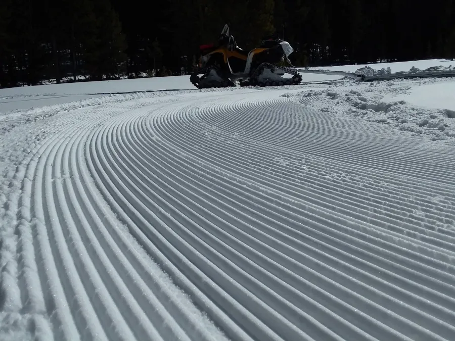 Fresh parallel corduroy groomer ridges on a cold morning snow surface